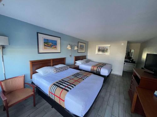 莱克威尔士Rodeway Inn的酒店客房,配有两张床和椅子
