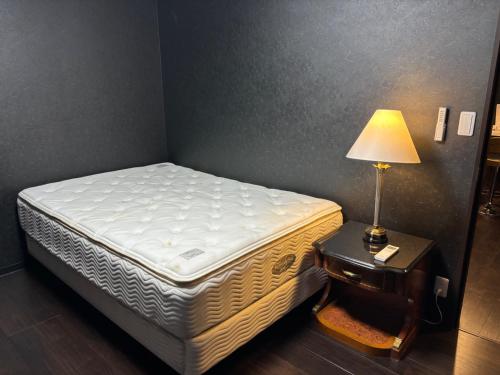 秋留野Tokurajyo - Vacation STAY 15813的一张床上的房间,桌子上有一盏灯