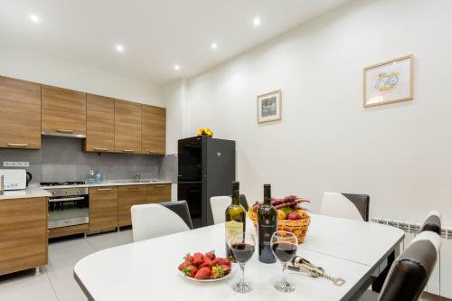 第比利斯Premium 2 Bedroom Apartment lll的厨房配有带葡萄酒瓶和一碗水果的桌子