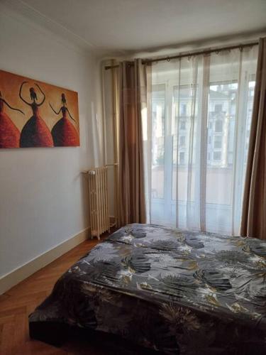 日内瓦Joli appartement aux Eaux Vives的卧室配有一张床,墙上挂有绘画作品