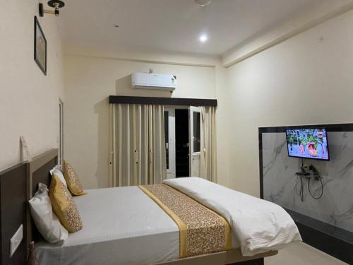 瓦拉纳西Hotel Nath Palace Chunar Road Varanasi - Luxury Room - Excellent Service Recommended的卧室配有一张床铺,墙上配有电视