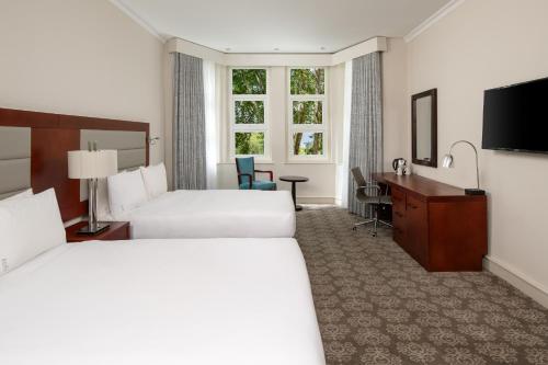 约翰内斯堡Holiday Inn - Johannesburg Sunnyside Park, an IHG Hotel的酒店客房配有两张床和一张书桌