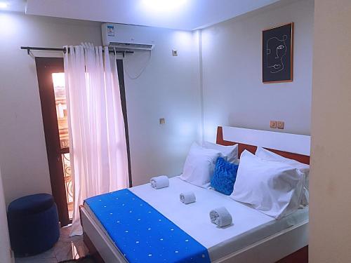 雅温得Le meublé des voyageurs的一间卧室配有一张带蓝色和白色枕头的床