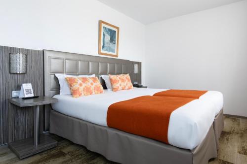 阿尔勒Hôtel Atrium的一间卧室配有一张带橙色毯子的大床