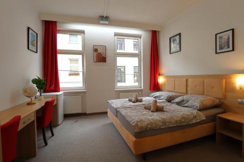 维也纳Golden’s Apart-Hotel的一间卧室配有一张床、一张书桌和两个窗户。