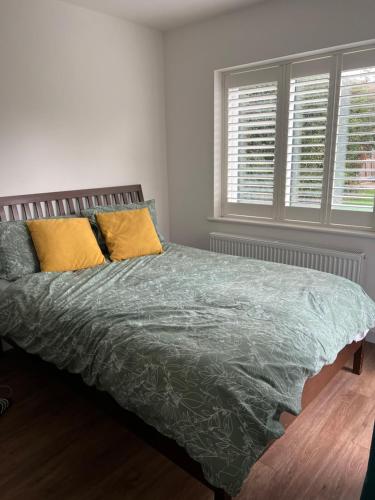 海华德希思12 Ganderhill的一间卧室配有一张带绿色棉被的床和两个窗户。