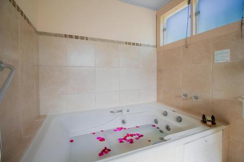 蒂拉登特斯阿莱格拉旅馆的浴室设有浴缸,上面有粉红色的鲜花