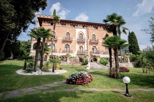 加尔多内-里维耶拉贝尔维尤酒店 的一座棕榈树和鲜花的大砖砌建筑