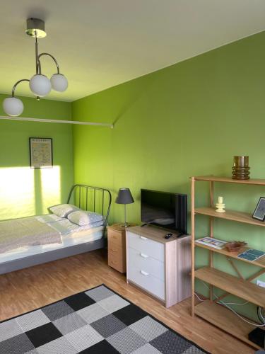 图尔库The Golden Glow Apartment Turku的一间带绿色墙壁的卧室、一张床和电视