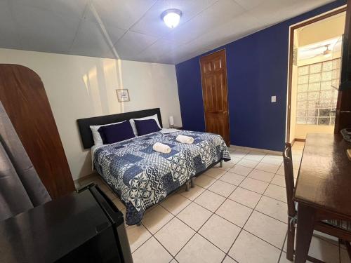 圣萨尔瓦多Hotel Sueños的一间卧室配有一张蓝色墙壁的床和一张桌子
