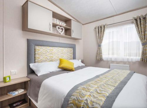 坎伯利SBL38 Caravan at Camber Sands - quiet location的一间卧室配有一张带黄色枕头的大床