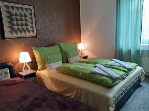 代姆延Varázsfa Vendégház的一间卧室配有一张带绿床单和枕头的床。