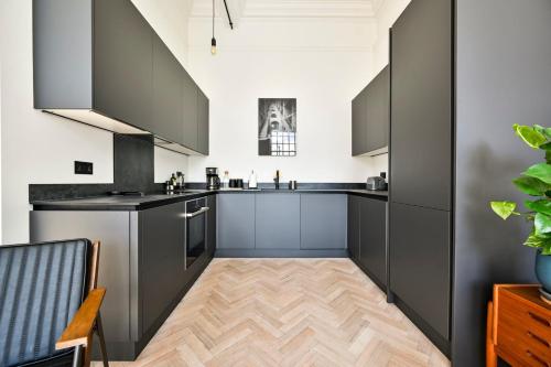 帕尔默斯格林GuestReady - Luxury haven in Palmers Green的厨房铺有木地板,配有灰色橱柜。