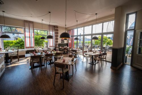 石勒苏益格阿尔特克雷斯班霍夫酒店的餐厅设有桌椅和大窗户。
