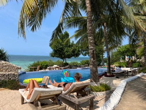 吉汶瓦Z-Lodge Zanzibar的两人躺在游泳池附近的躺椅上