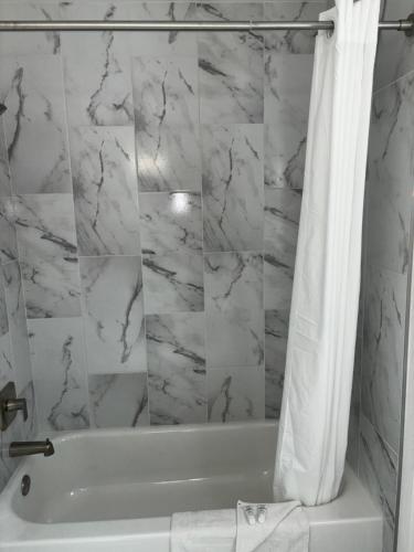 博尔德城Boulder City Inn的白色的浴室设有浴缸和淋浴帘