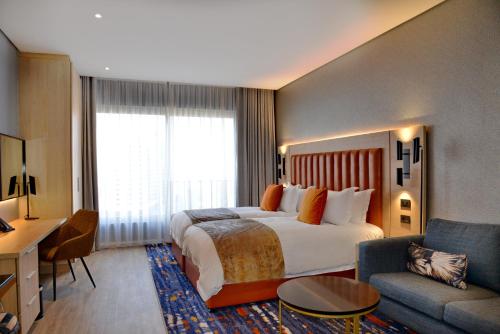 约翰内斯堡@Sandton Hotel的酒店客房设有一张大床和一张沙发。
