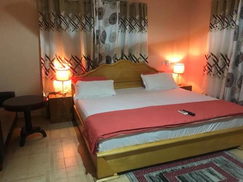 AsamankeseJEMP INN HOTEL的一间卧室配有一张大床、两盏灯和一张桌子