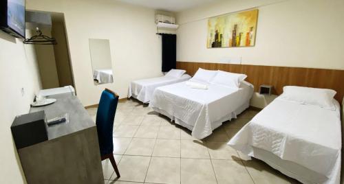 伊瓜苏Itaipu Hotel Foz do Iguaçu的客房设有两张床、一张桌子和一张书桌。