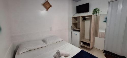 阿尔特杜尚Pousada Angatu alter的一间白色的小卧室,配有一张床和一台电视