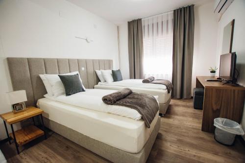 斯特鲁米察Urban Studio Apartments的酒店客房设有两张床和电视。