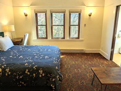 波特兰蓝鸟宾馆的卧室配有床、桌子和窗户。