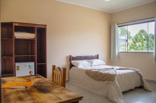 伊塔蒙蒂Hotel Águas Lindas的一间卧室配有一张床、一张桌子和一个窗户。
