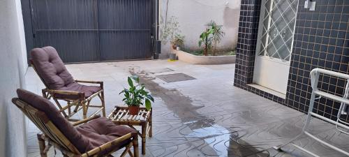 阿雷格里港Aloha Hostel&CoWorking - Prox Aeroporto e Consulado的庭院里摆放着两把椅子,种植了盆栽植物