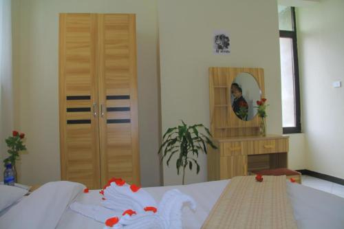 Debre ZeyitEkshesh Hotel Bishoftu的一间卧室配有床、镜子和姑娘