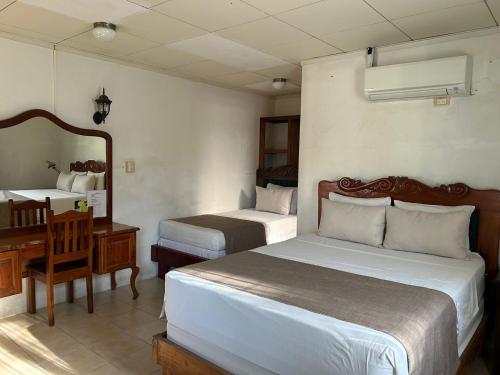利比里亚Hotel Javy的酒店客房配有两张床、一张书桌和一张书桌。