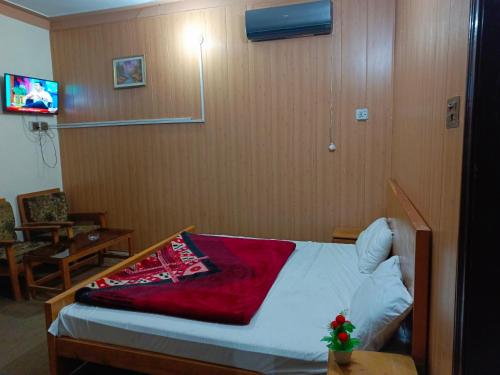 穆扎法拉巴德SEE MOTEL的一间卧室配有一张床铺,床上铺有红色毯子