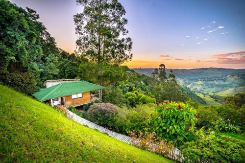 萨兰托Hotel Kawa Mountain Retreat的山丘上的小屋,拥有绿色的屋顶