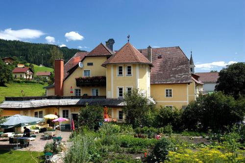 ThörlLandhotel Restaurant Hubinger的一座黄色的大房子,前面有一个花园