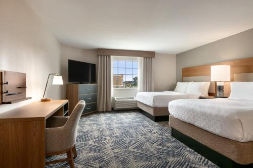 河边城Candlewood Suites Aberdeen-Bel Air, an IHG Hotel的酒店客房设有两张床、一张桌子和一台电视。