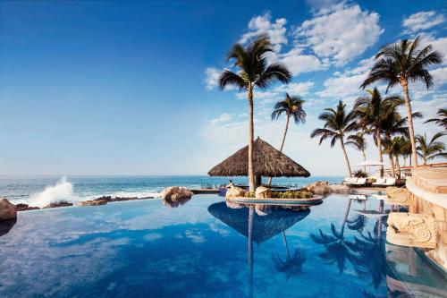 圣何塞德尔卡沃帕米拉独一无二酒店的棕榈树和海洋度假村的游泳池