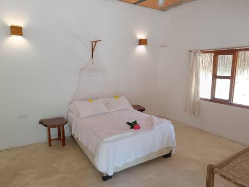 GuachacaSierra Sagrada Tayrona的卧室配有白色的床,床上有花
