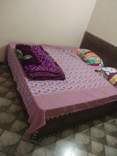 马图拉Gaurangi seva sadan的一张带紫色被子和枕头的床