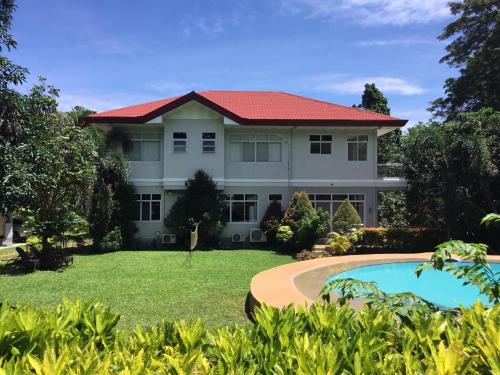 曼巴豪Camiguin Lanzones Resort的一座大型白色房屋,设有红色屋顶