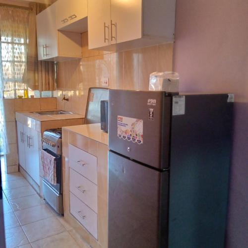 ThikaVerona Apartments的厨房配有黑冰箱和白色橱柜。