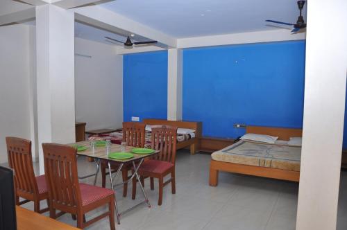 库斯哈尔纳加尔Vinayaka Deluxe Lodge的一间配备有桌椅和蓝色墙壁的餐厅
