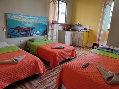 阿约拉港Mí oficina的一间设有3张床的客房,配有橙色和绿色的床单