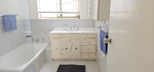 珀斯Peaceful House的白色的浴室设有水槽、浴缸和浴缸。