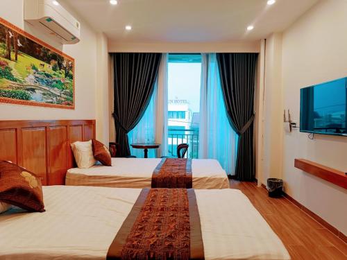 顺化PHƯƠNG ĐÔNG HUẾ HOMESTAY的酒店客房设有两张床和一台平面电视。