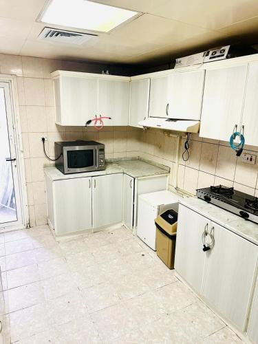 阿布扎比MKB APARTMENTS的厨房配有白色橱柜和微波炉