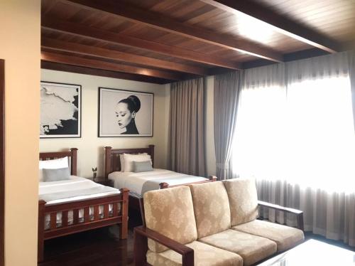 巴色雅典娜酒店的一间卧室设有两张床、一张沙发和一个窗口