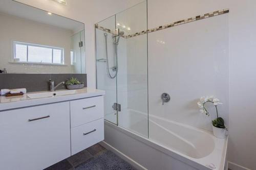 旺阿雷Rest & Relax Villa Whangarei的带淋浴和盥洗盆的白色浴室