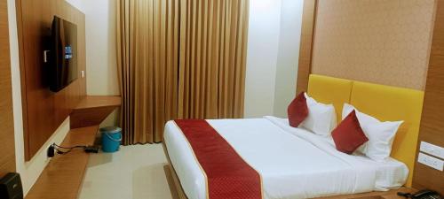 蒂鲁帕蒂HOTEL ORCHID VISTA的一间卧室配有带白色床单和红色枕头的床。