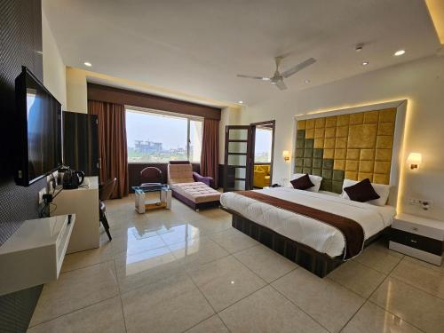 巴罗达Hotel Grand Darshan Vadodara的酒店客房设有一张大床和一台电视。