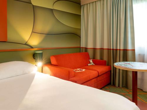 利雪Ibis Styles Lisieux Normandie的一间卧室配有一张床、一把椅子和一张桌子