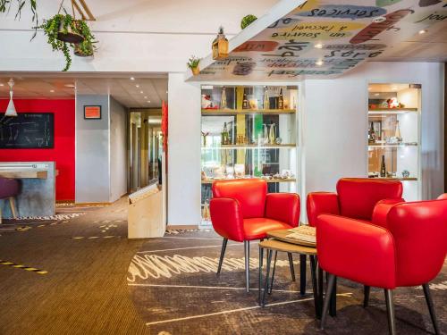 科尔马ibis Colmar Est - Hotel Restaurant en Alsace的一间带红色椅子和桌子的餐厅